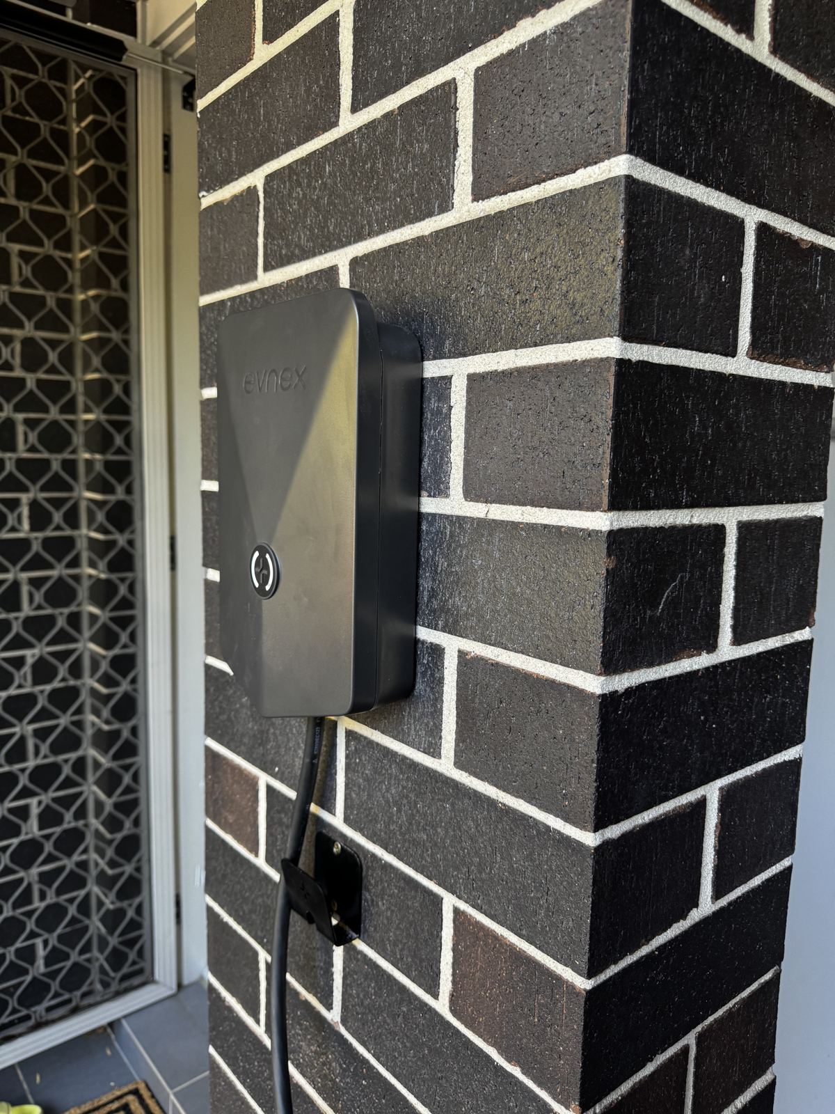 EV charger installed on a rendered brick wall